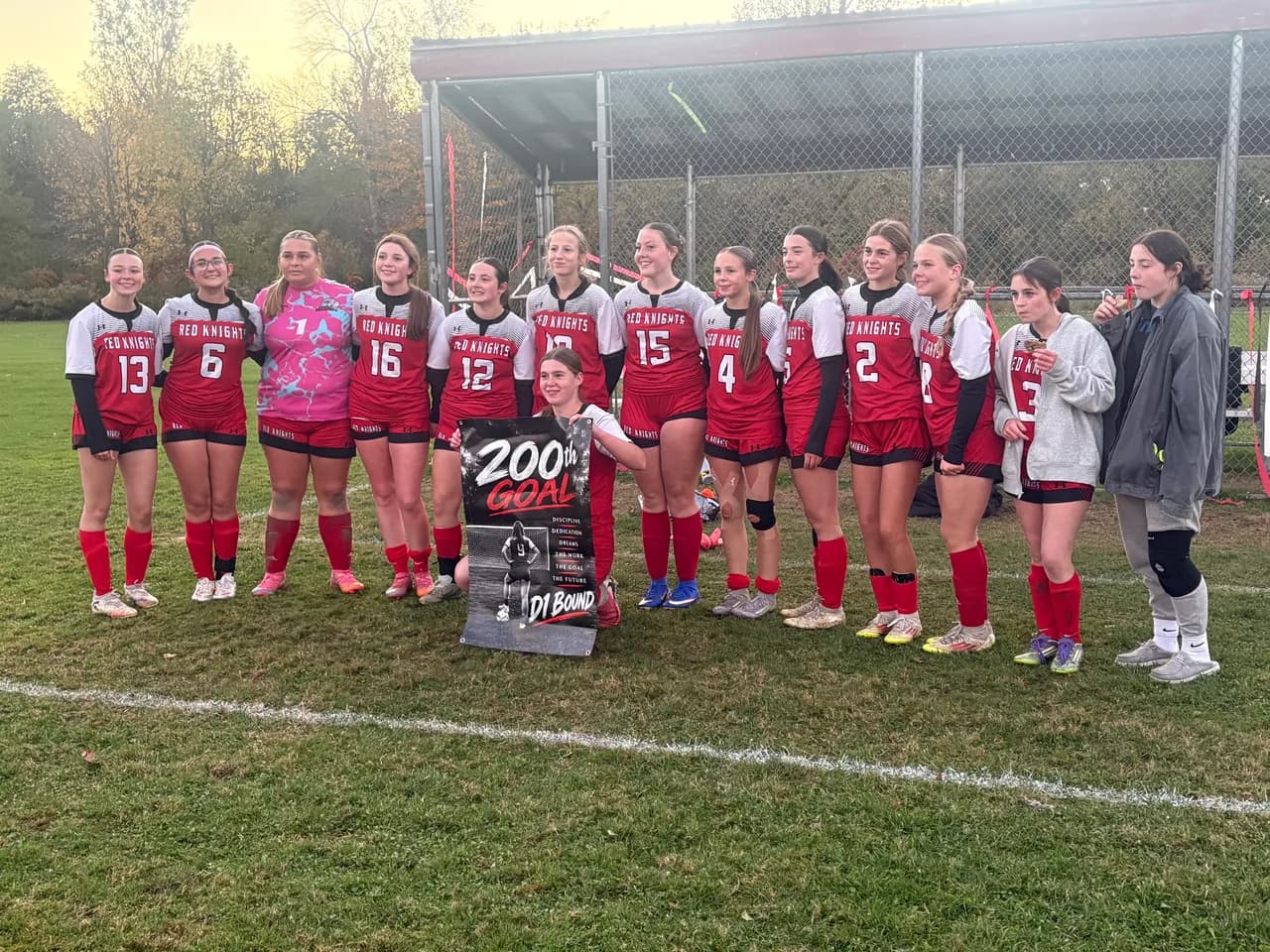 Elyza Smith holds a commemorative 200th-goal sign alongside La Fargeville teammates after scoring five goals in the Red Knights' 5-1 senior night win over Alexandria Bay. Smith finished the game with 204 varsity career goals.